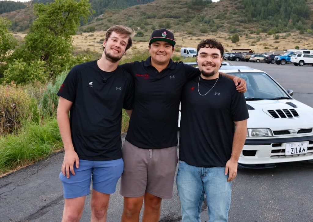 The EISHIN AUTO crew standing together in front of a white Nissan at a Colorado car meet